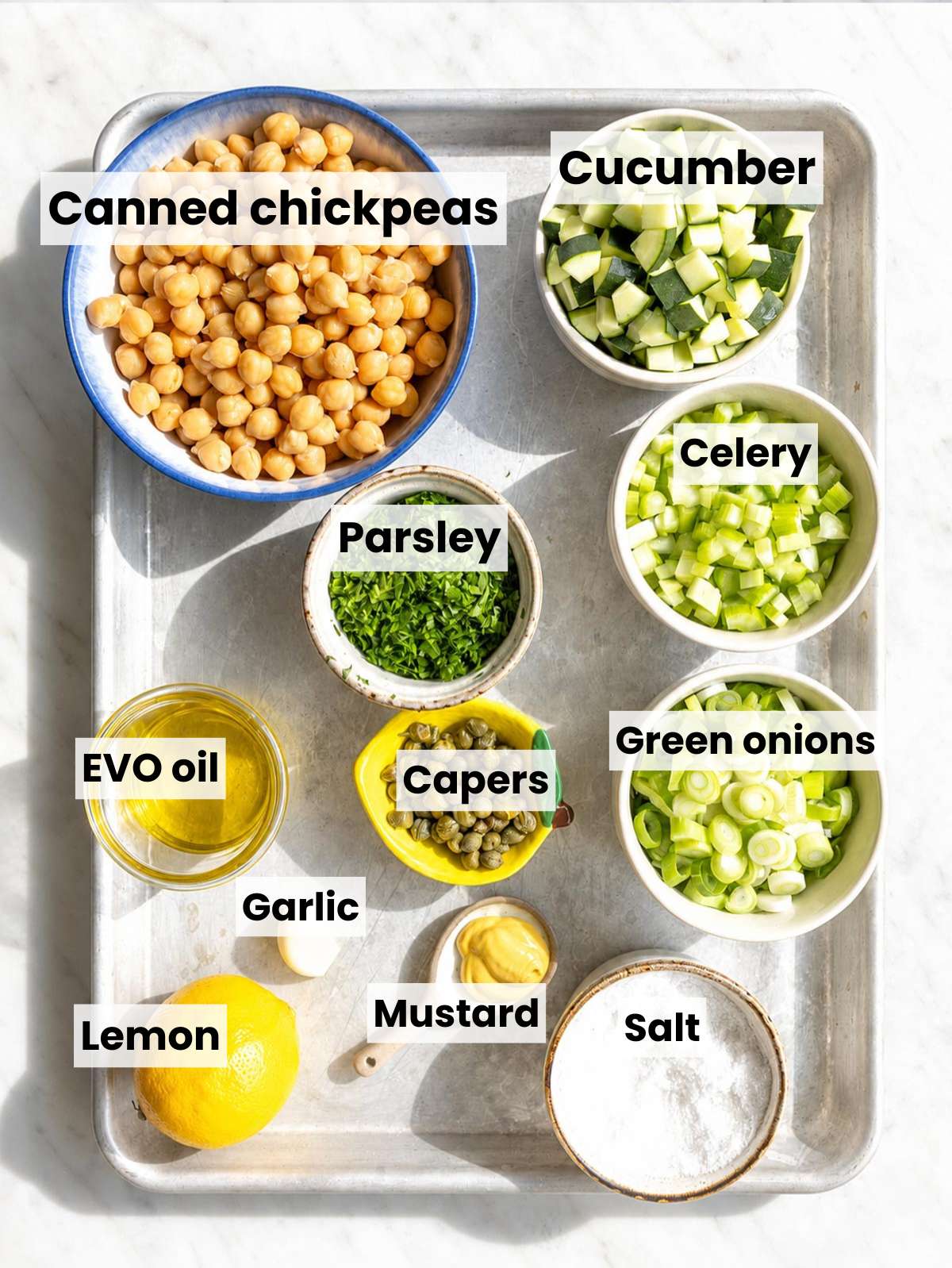 Ingredients for Piccata Chickpea Salad on white marble in natural window light.