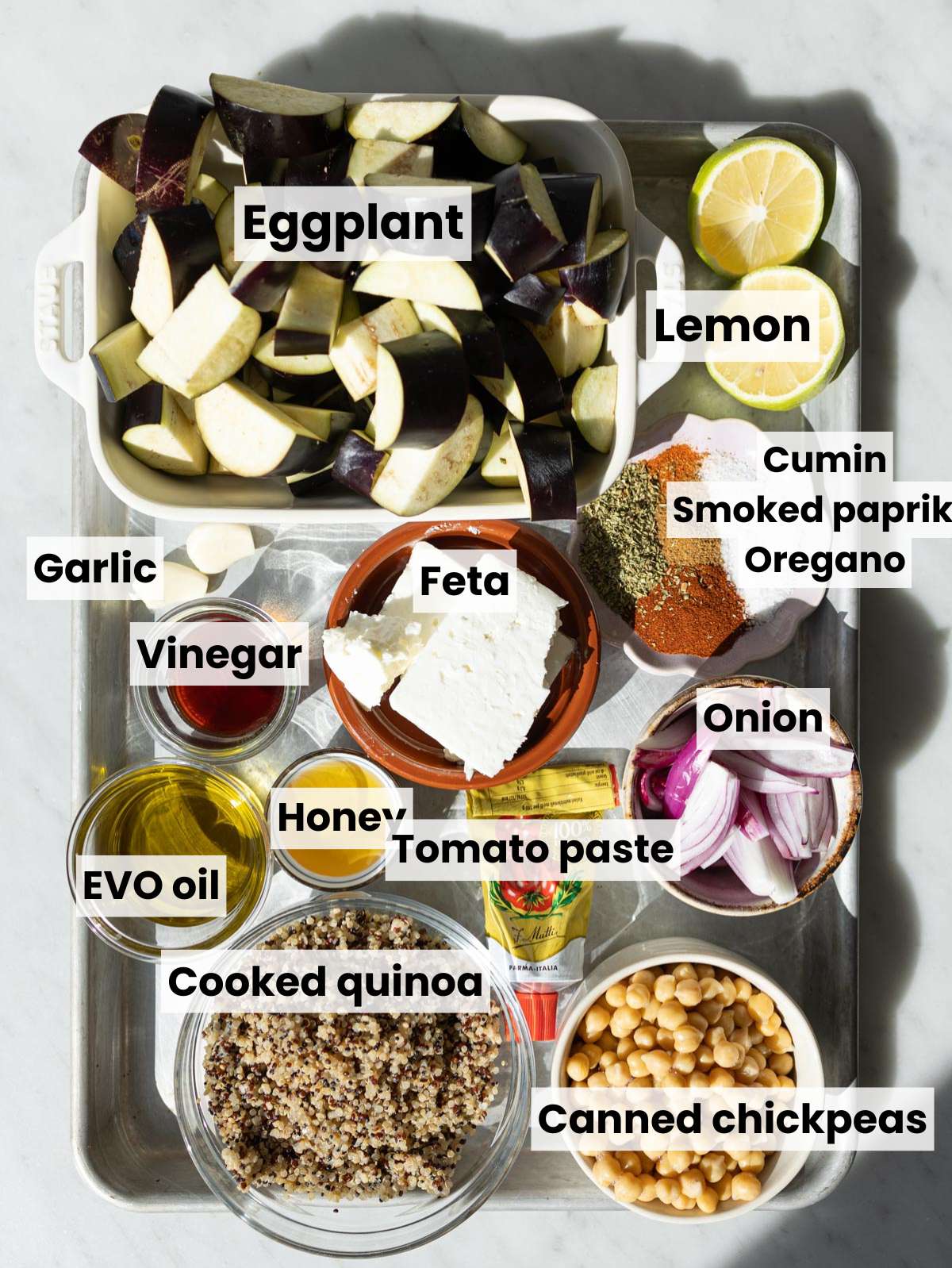 Ingredients for Roasted Eggplant Gyros Bowl arranged on a white marble surface.