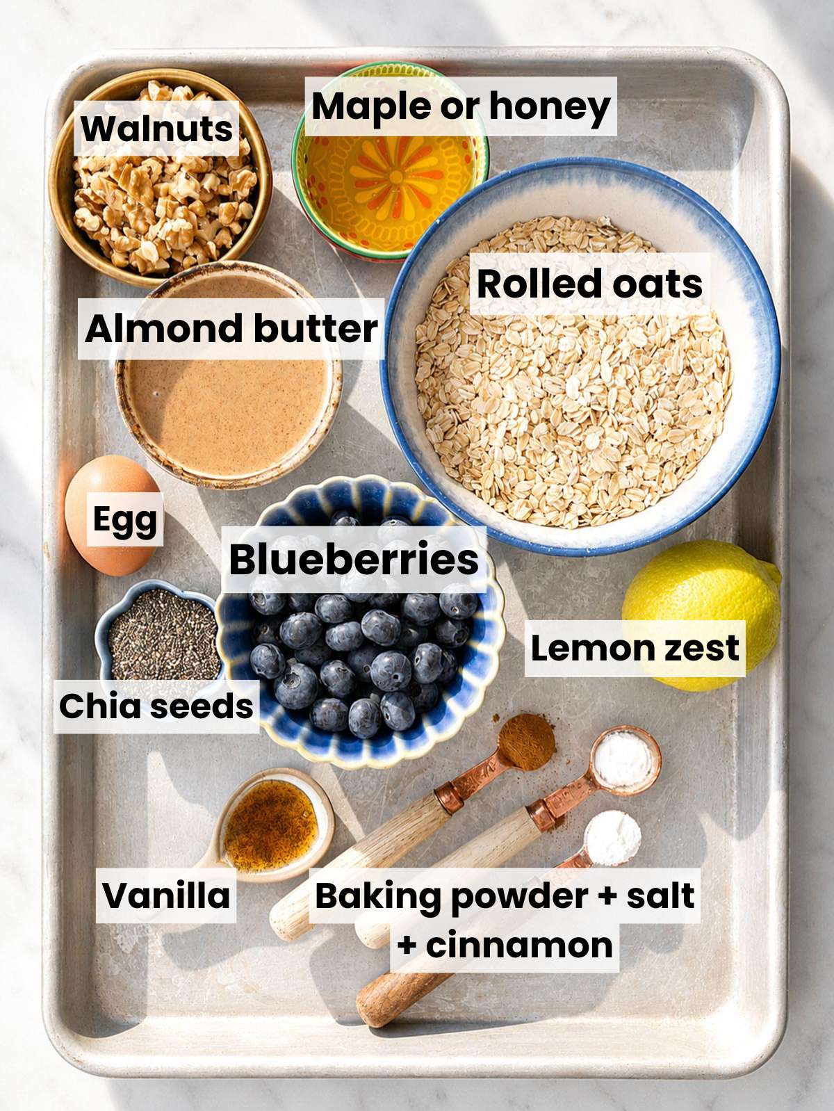 Ingredients for oatmeal blueberry cookies on white marble in natural daylight.