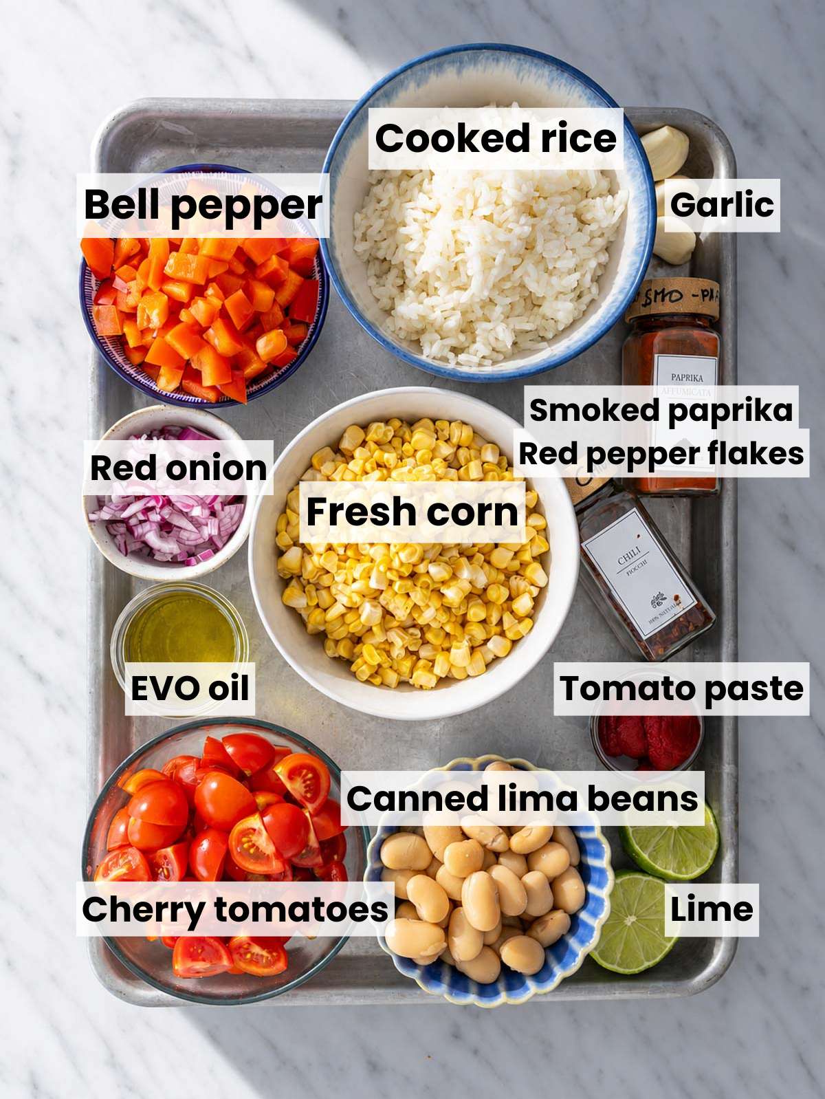 Ingredients for summer succotash rice bowl arranged on a light marble countertop.
