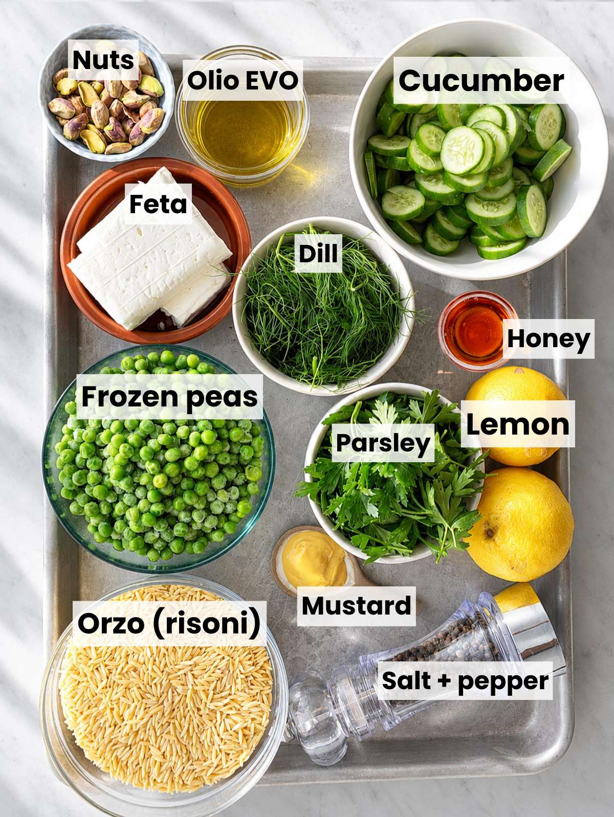Lemon orzo salad ingredients on white marble counter in bright natural window light.