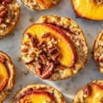 Peach cobbler baked oatmeal cups with glossy peaches in bright natural window light.