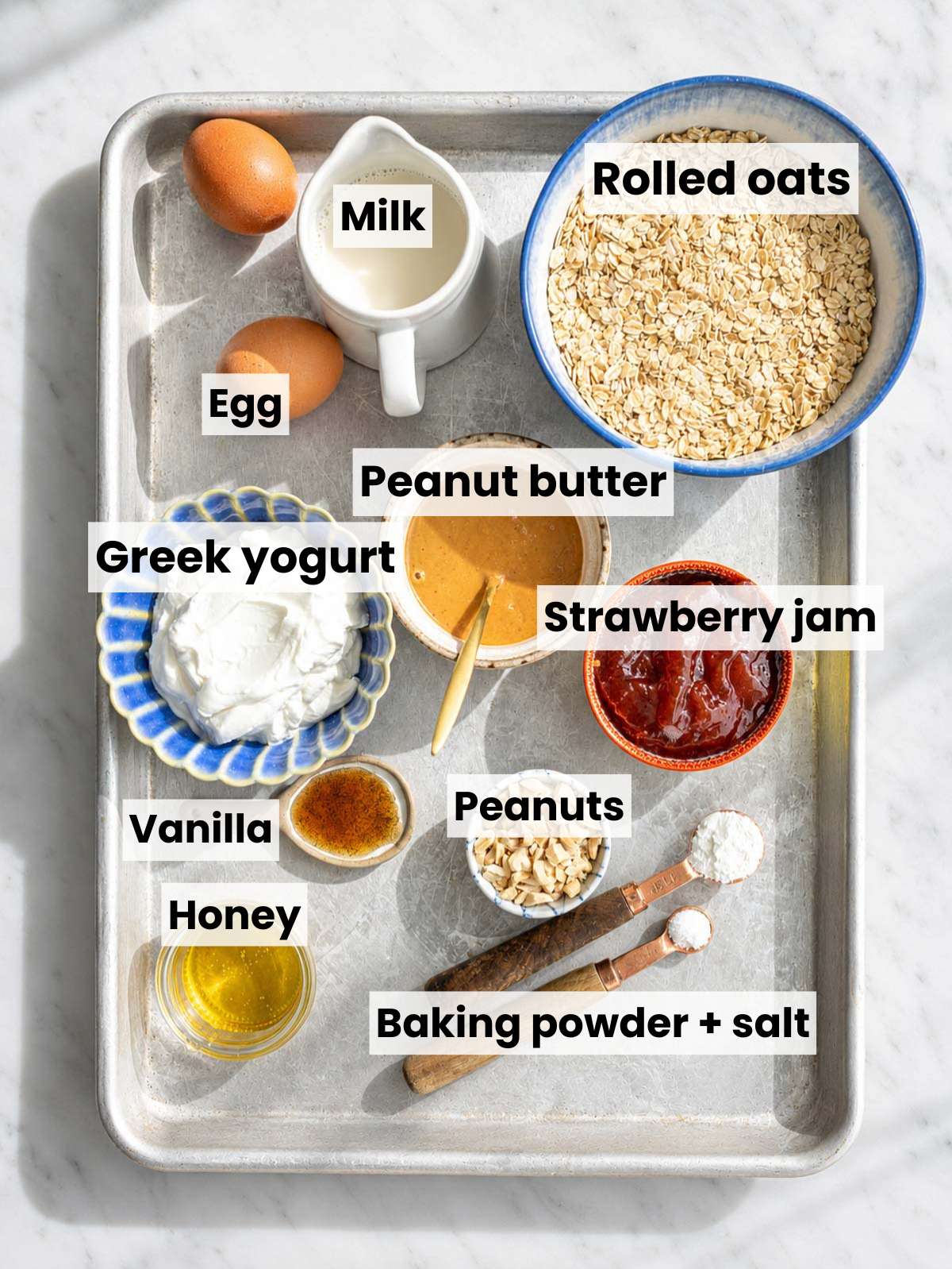 Peanut Butter and Jelly Baked Oatmeal ingredients on white marble in natural daylight.
