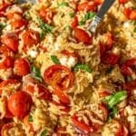 Roasted tomato orzo on sheet pan with a serving spoon.