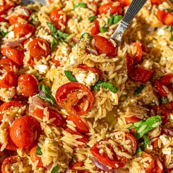 Roasted tomato orzo on sheet pan with a serving spoon.