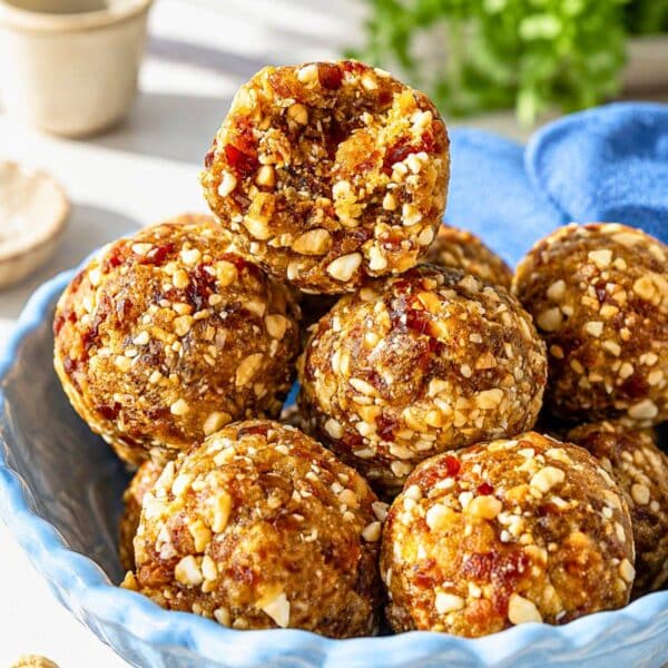 Salted Cashew Caramel Energy Balls in bowl on white marble with sea salt.