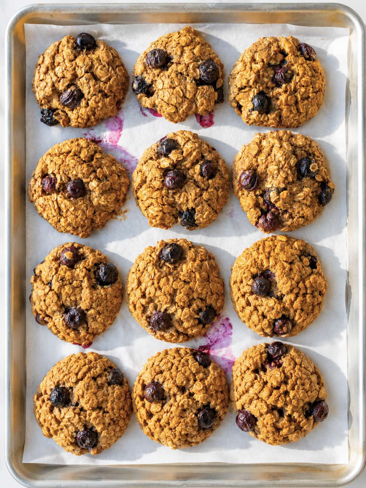 Sheet pan of oatmeal blueberry cookies with fresh blueberries.
