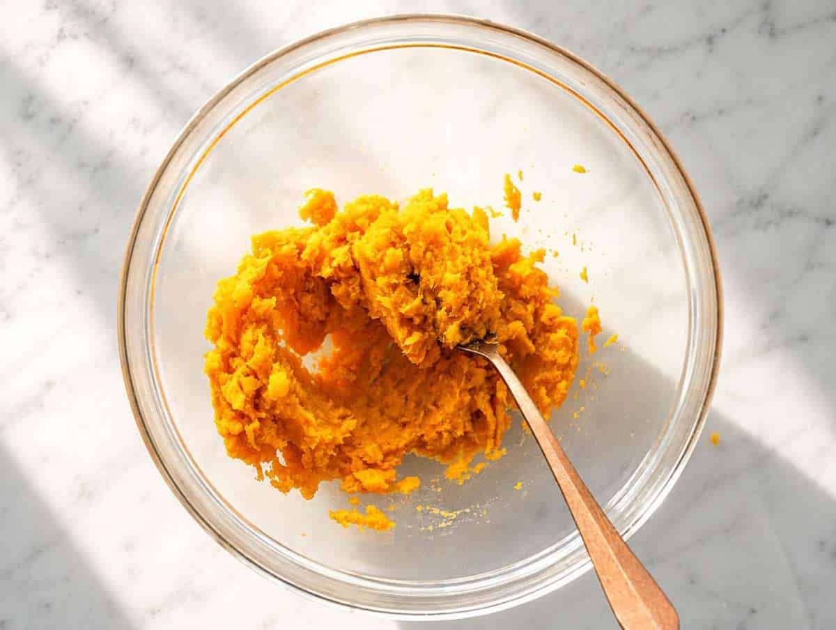 Step 1 Mashed sweet potatoes in bowl on white marble.