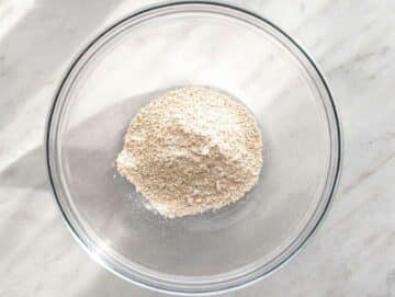 Step 1 Rolled oats blending into fine oat flour in a food processor on marble countertop.