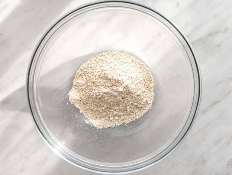 Step 1 Rolled oats blending into fine oat flour in a food processor on marble countertop.