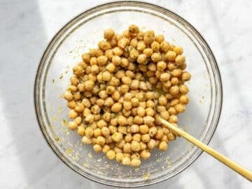Step 2 Chickpeas marinating in glossy lemon piccata dressing inside a large bowl.
