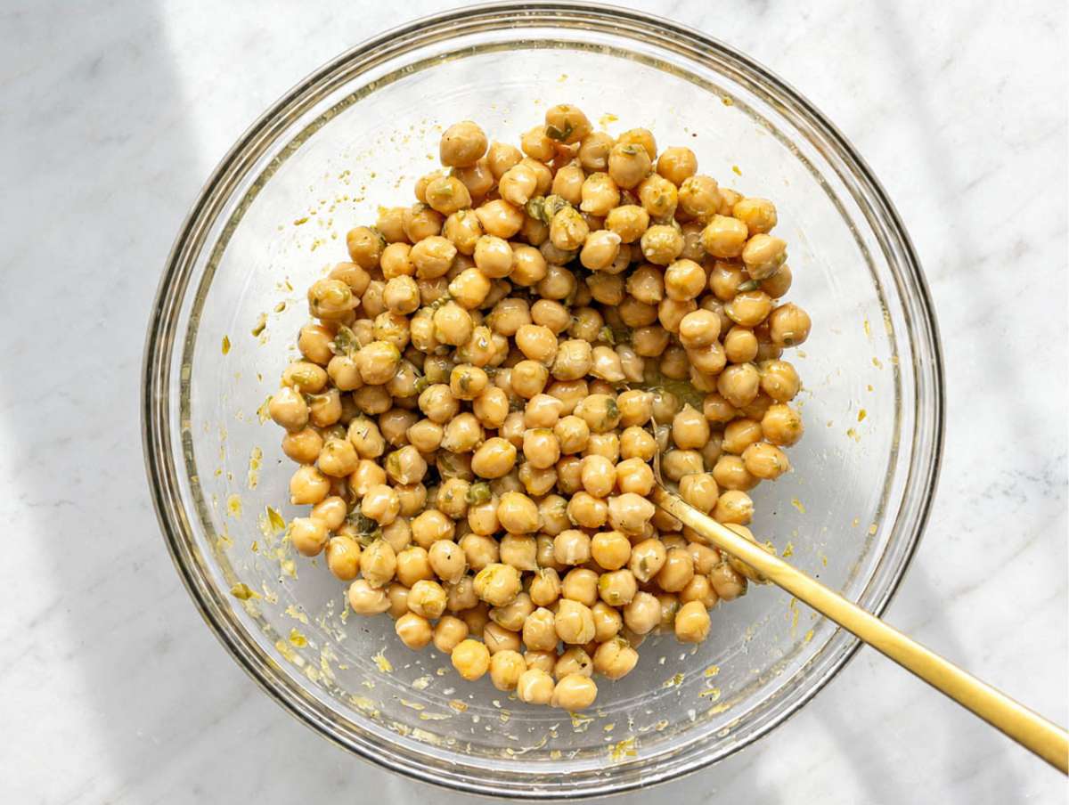 Step 2 Chickpeas marinating in glossy lemon piccata dressing inside a large bowl.