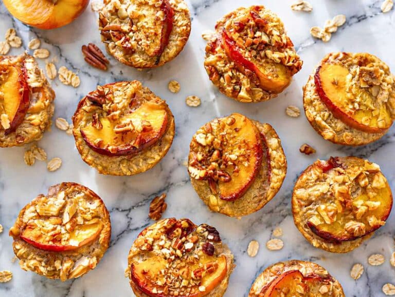 Step 4 Baked oatmeal cups cooling in muffin pan with golden tops and glossy peaches.