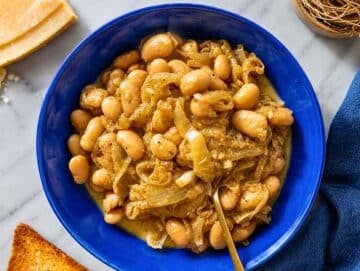 Step 4 French onion butter beans served with toasted sourdough on white marble.
