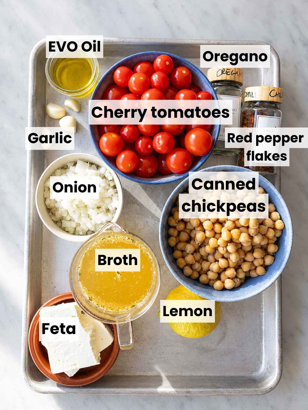 Tomato chickpea soup ingredients on white marble in bright natural window light.