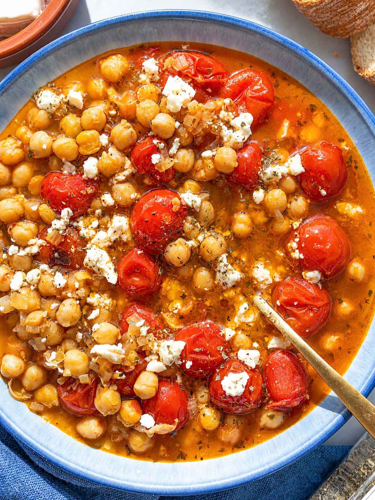 Tomato chickpea soup with feta and olive oil on marble.