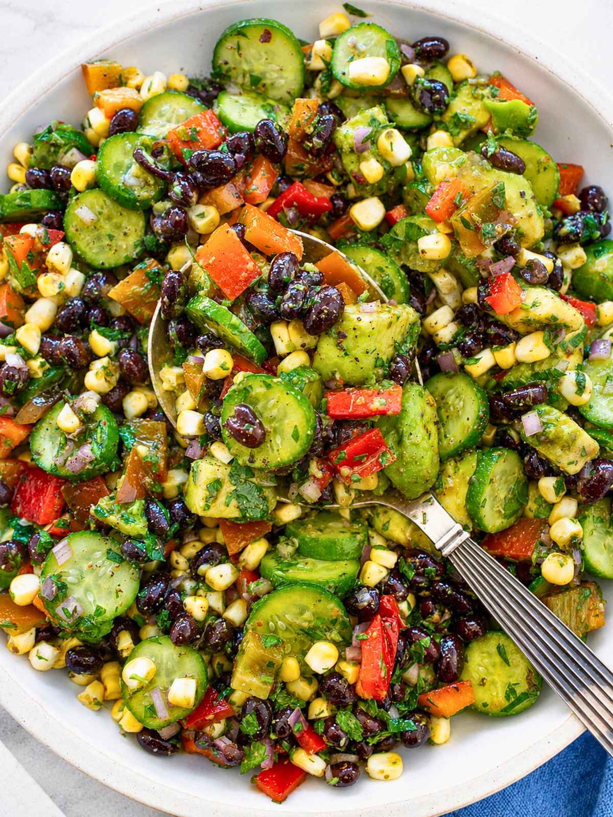 Top down of glossy black beans, corn, avocado, and fresh chimichurri dressing.