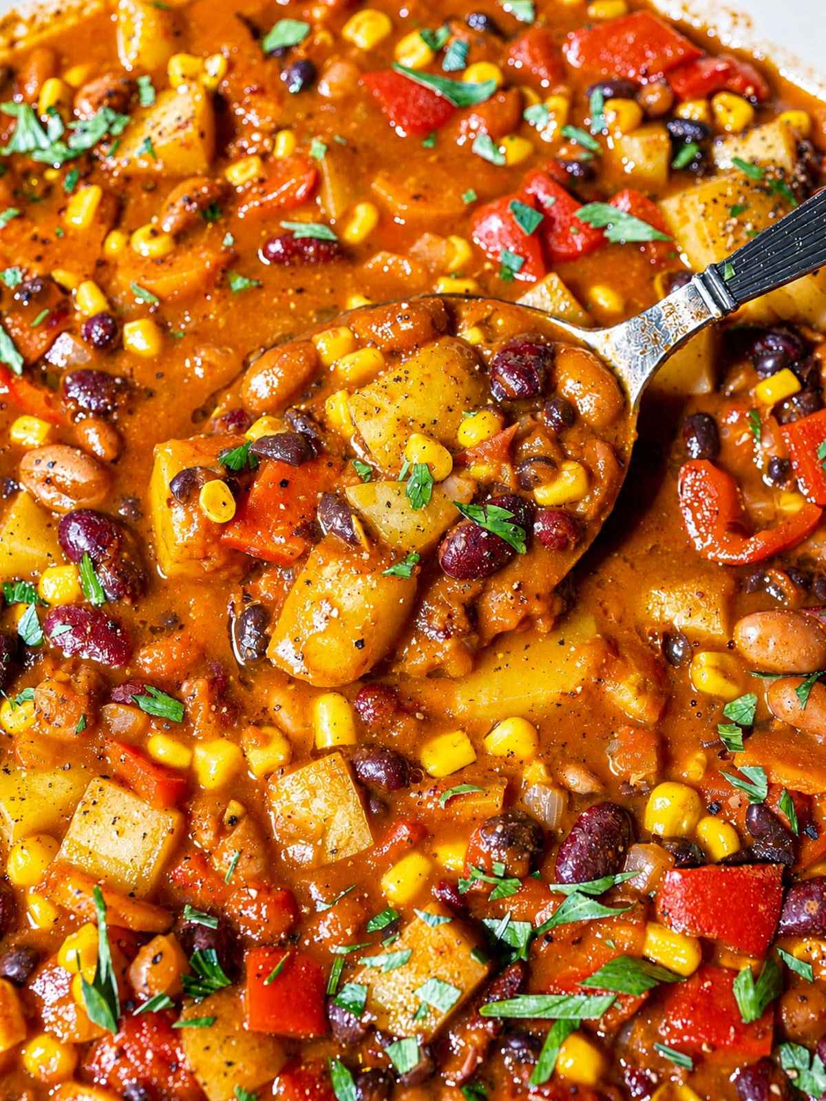 Close-up of Cowboy Bean Soup with a spoon lifting tender beans, potatoes, and corn.