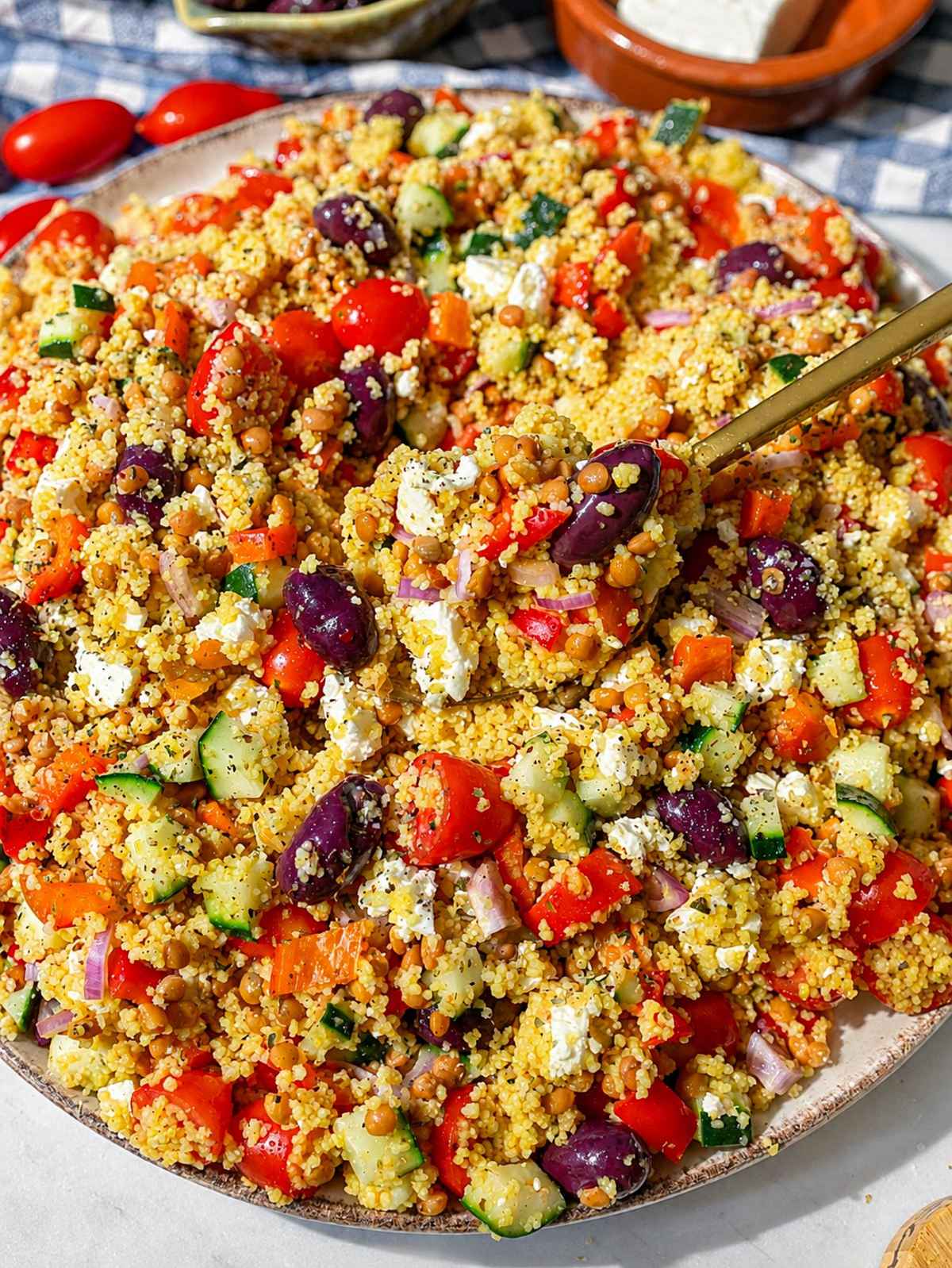 Close-up of Greek couscous salad with lentils, vegetables, and crumbled feta.
