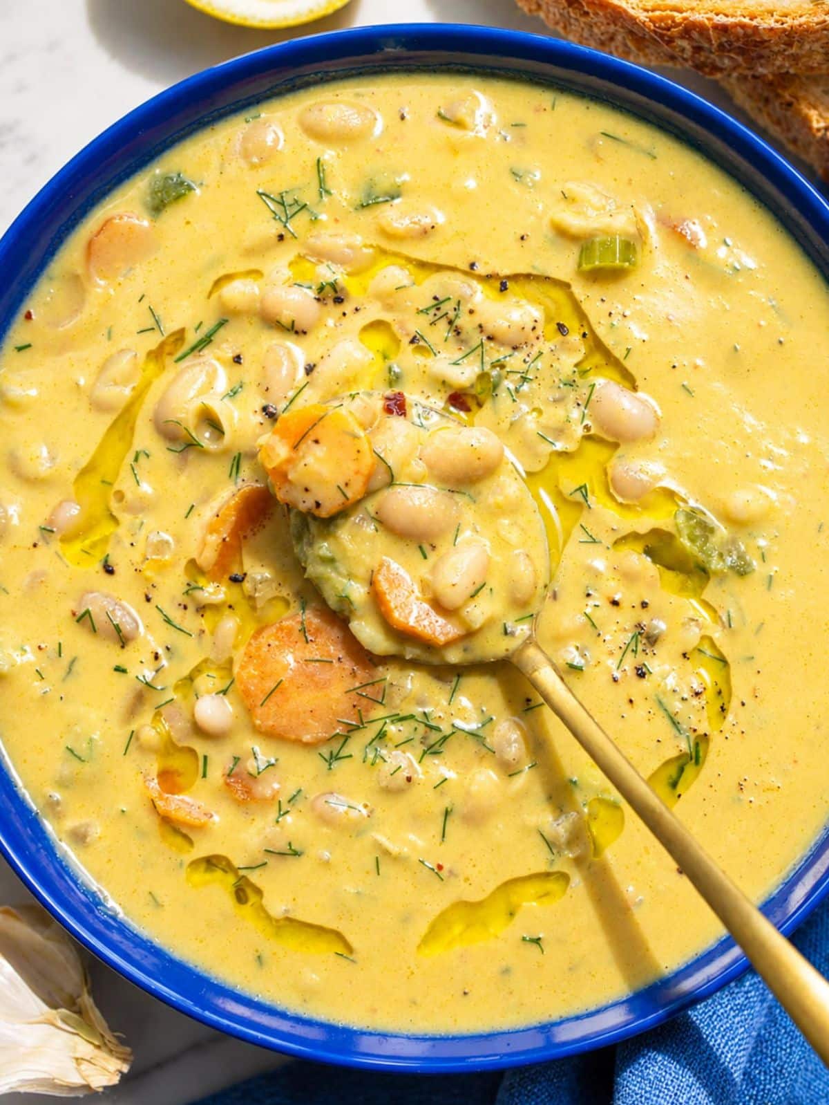 Close-up of creamy white bean soup with glossy beans and fresh dill.