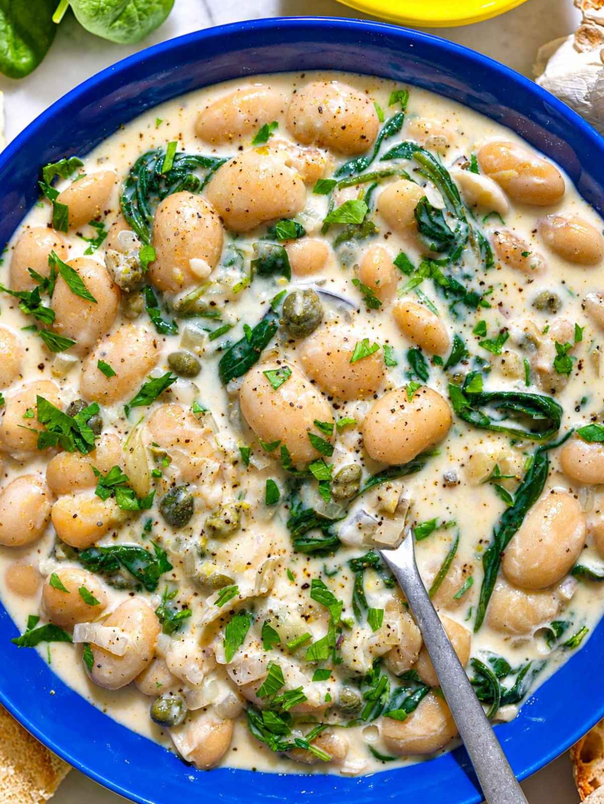 Close-up of glossy butter beans coated in creamy lemon caper sauce.