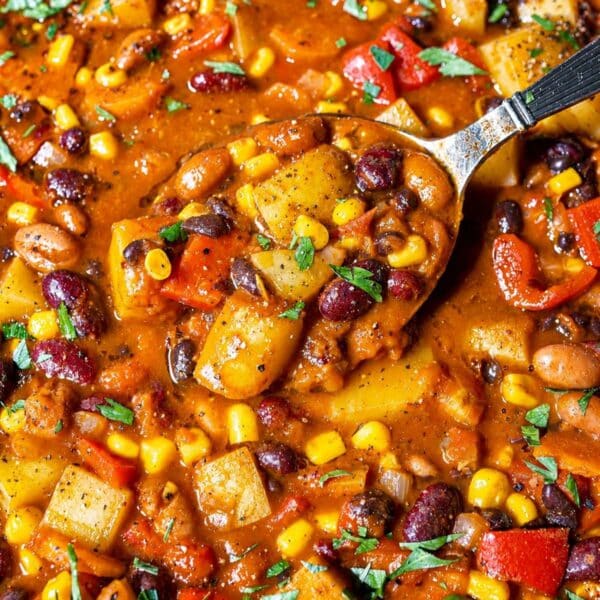 Cowboy Bean Soup with spoon lifting three beans, potatoes, corn, and tomato broth.