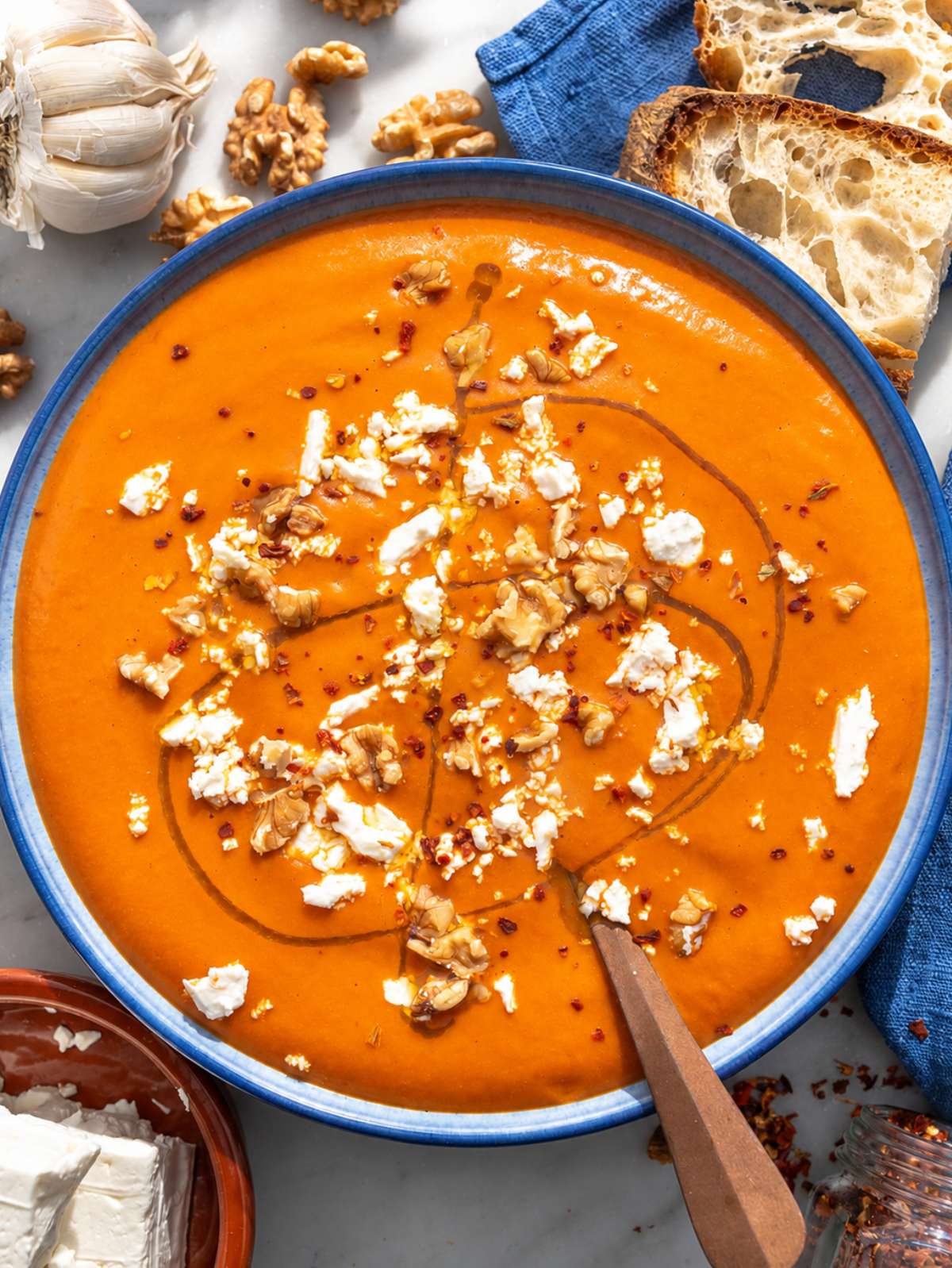 Creamy roasted red pepper soup topped with walnuts, feta, and olive oil.