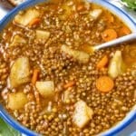 Hearty French lentil soup with crushed pepper and crusty bread on marble.