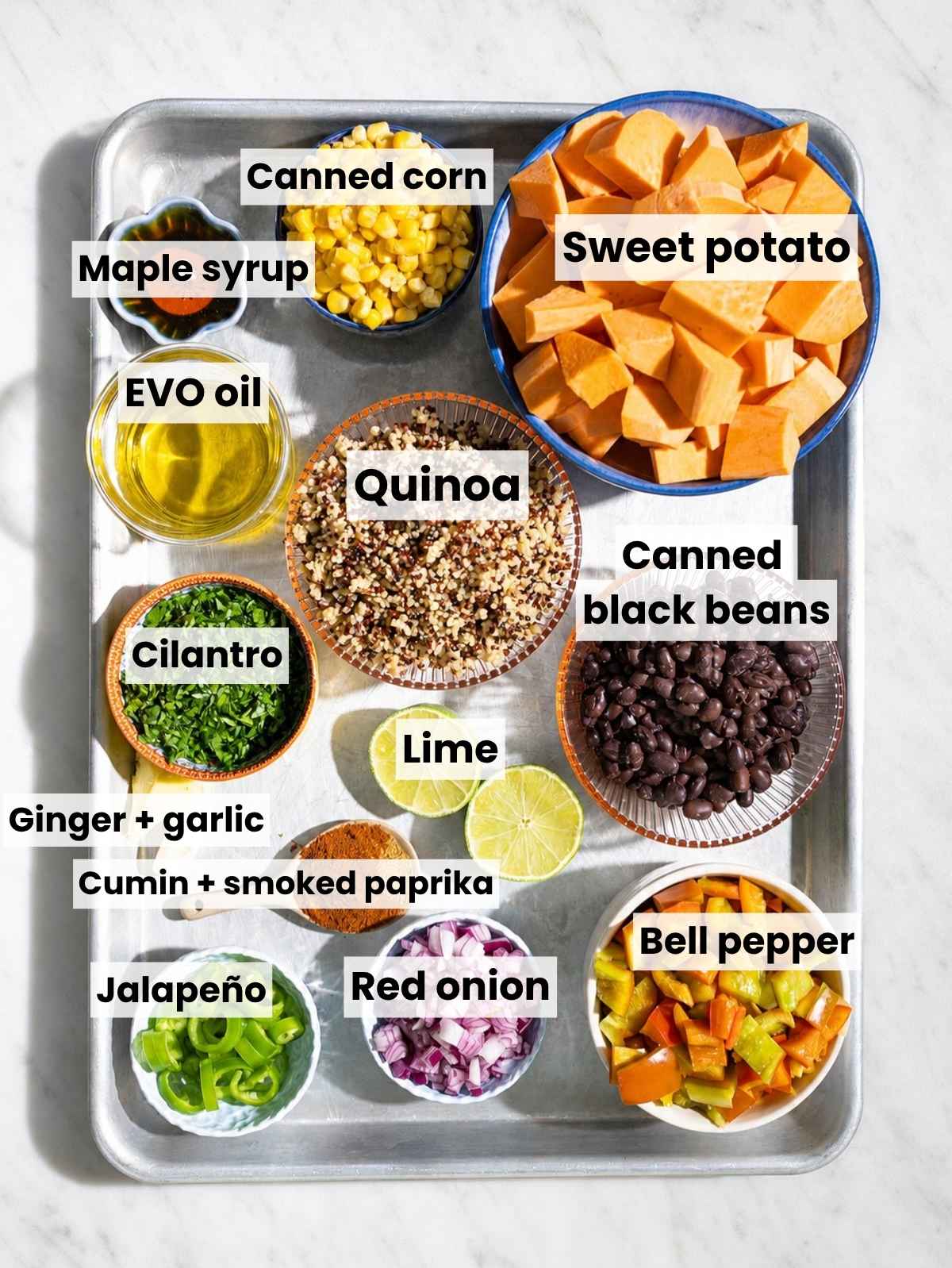 Mexican quinoa salad ingredients arranged on white marble in natural light