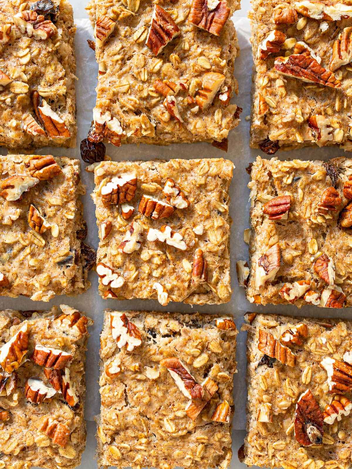 Oatmeal raisin baked oatmeal sliced with pecans on white baking paper on marble.