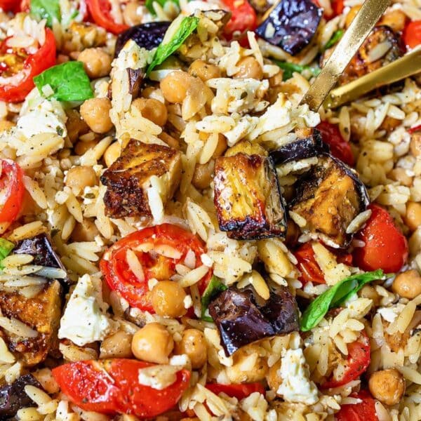 Roasted charred eggplant orzo topped with feta and basil in natural light.
