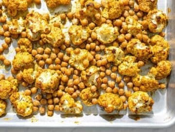 Step 2 Roasted chickpeas scattered around coated cauliflower florets on a sheet pan.
