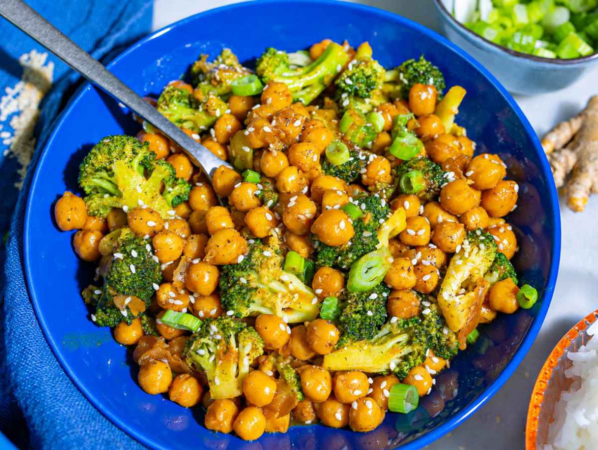 Step 4 Glossy sesame sauce coating chickpeas and broccoli in a blue bowl.