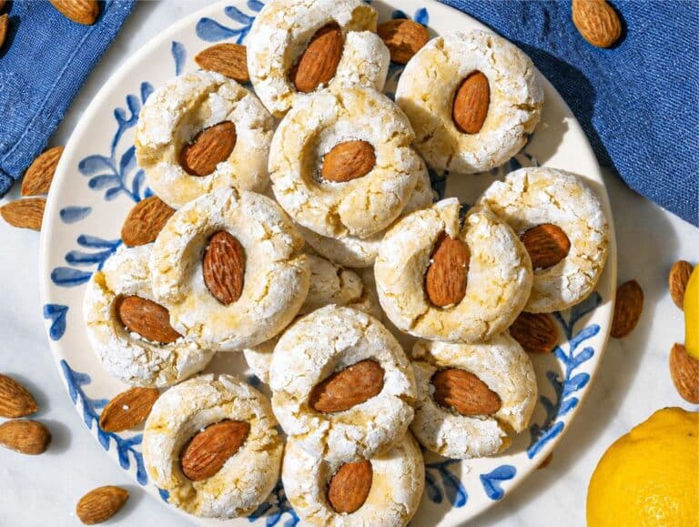 Step 4 Pale, crackled Lemon Almond Cookies cooling on a blue plate.