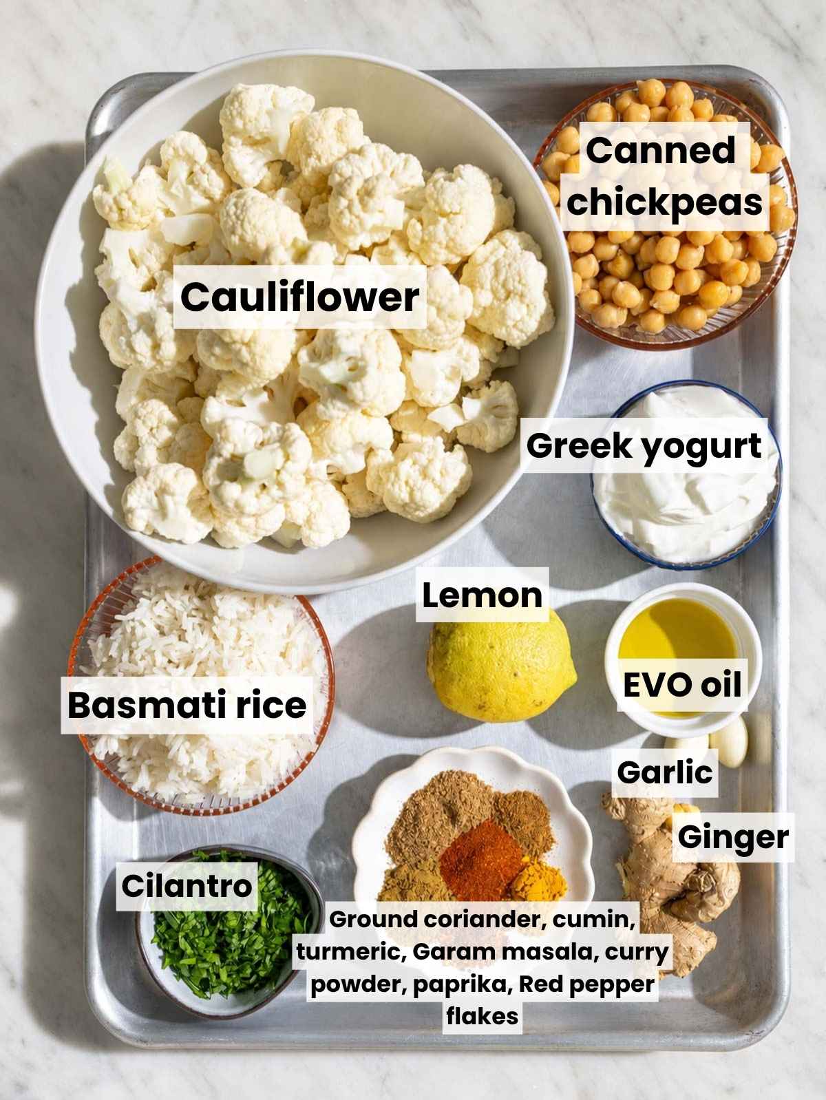 Tandoori cauliflower bowl ingredients on marble in natural daylight.