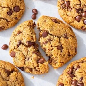 Almond butter chocolate chip cookies opened and lined together on baking sheet.