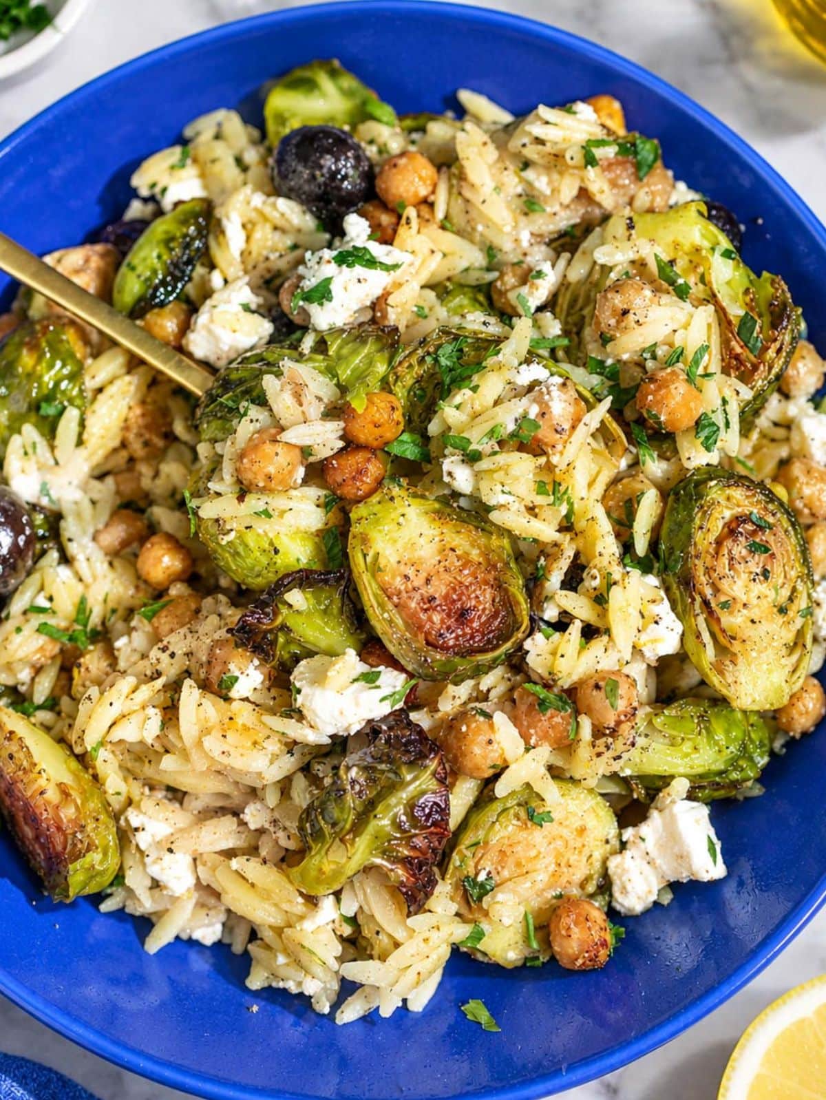 Roasted Brussels sprouts orzo with chickpeas, feta, olives, and parsley in a bowl.