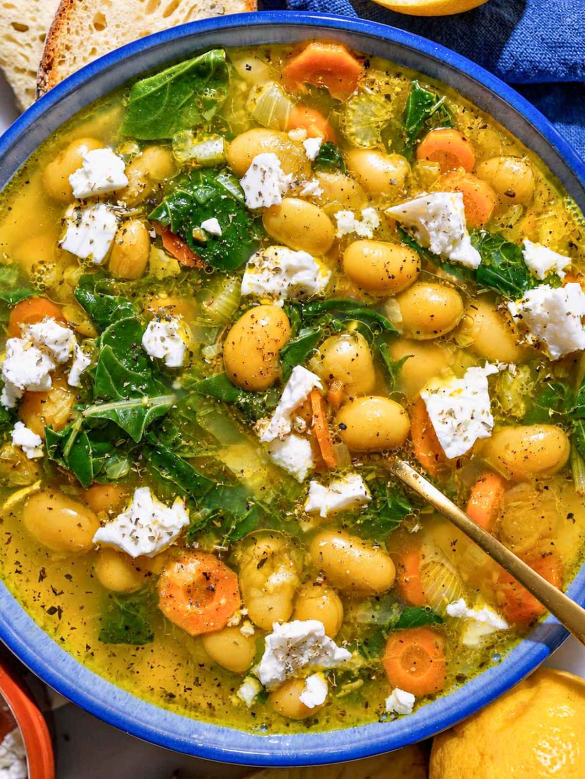 Top down of glossy butter beans, spinach, feta, and golden broth