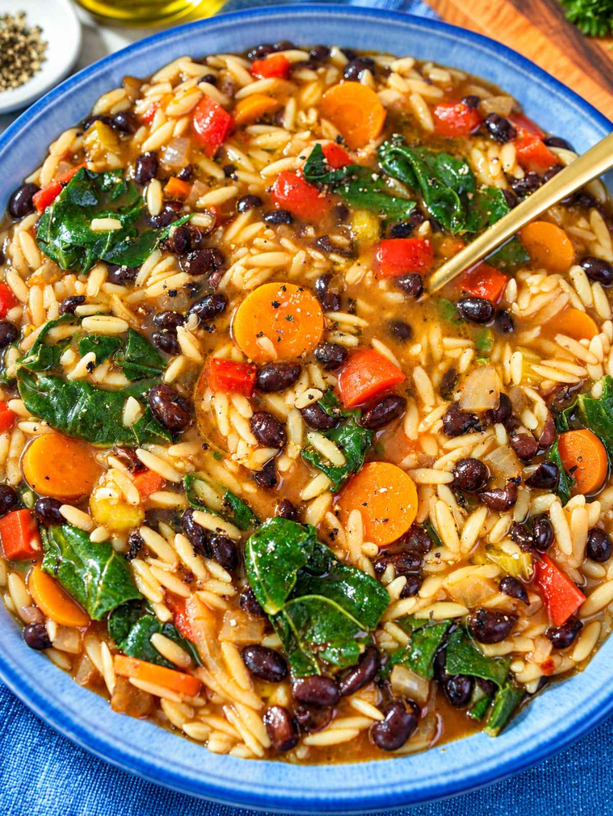 Black bean orzo soup with carrots, bell pepper, and spinach in a bowl.