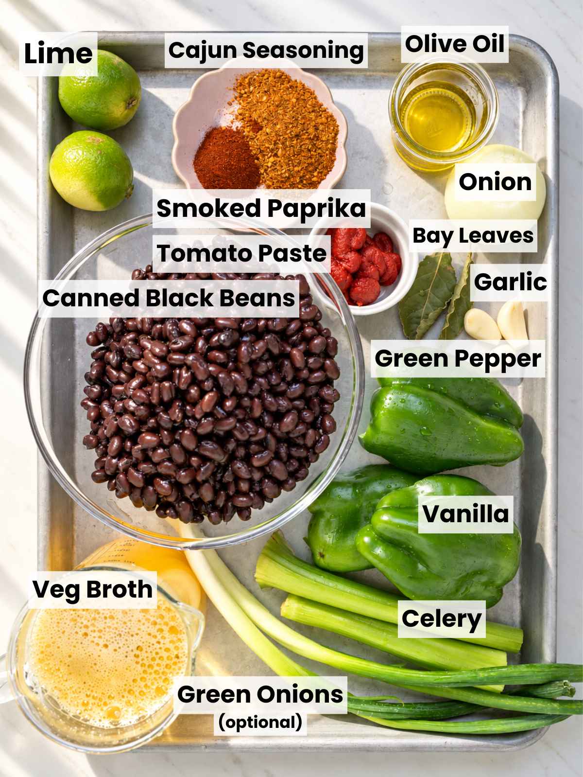 Black beans, bell pepper, celery, onion, spices, and other soup ingredients arranged on marble.