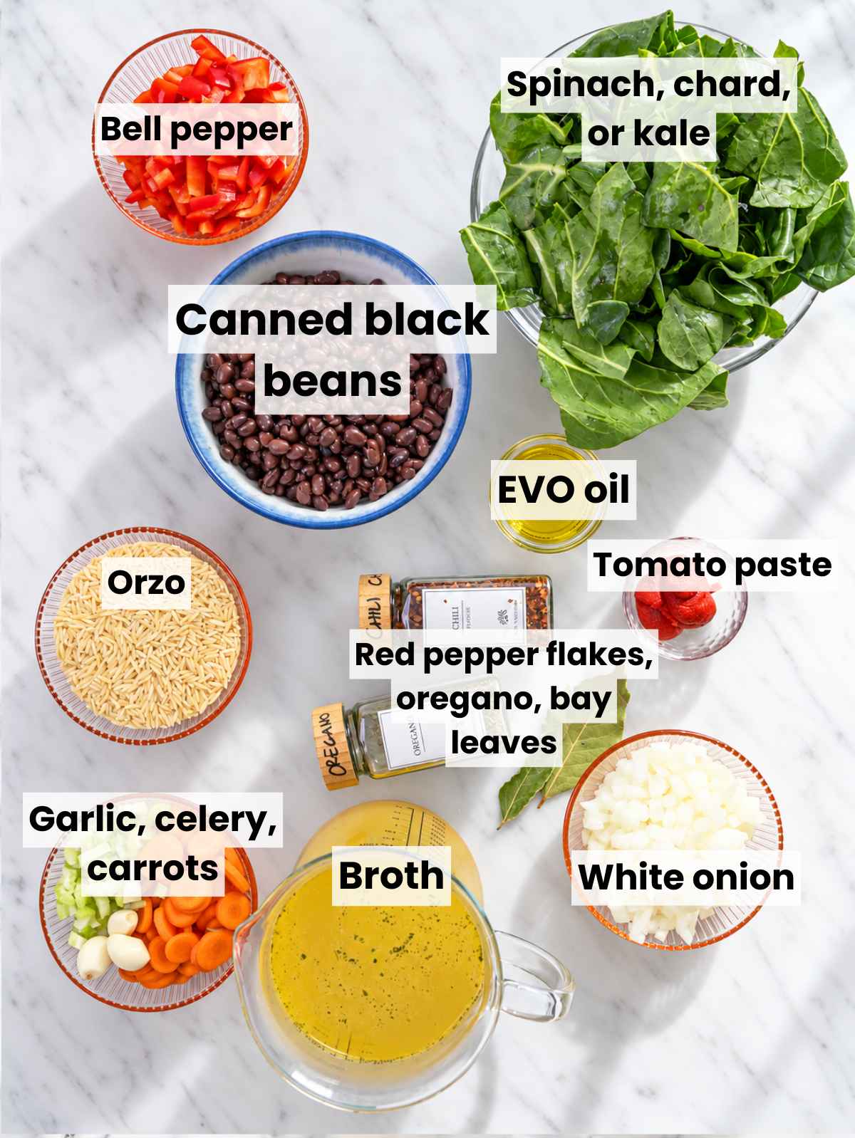 Black beans, orzo, spinach, vegetables, broth, tomato paste, and seasonings on marble.