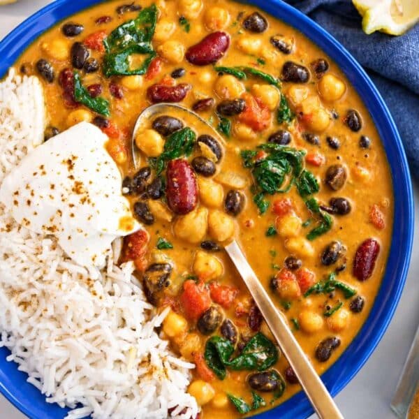 Bowl of three bean curry with fluffy rice, spinach and yogurt.