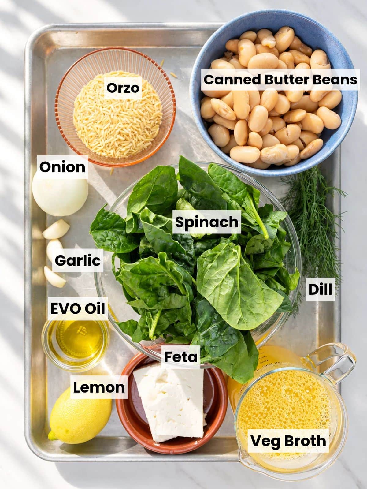 Butter beans, orzo, spinach, feta, lemon, garlic, onion, and fresh dill on a table.