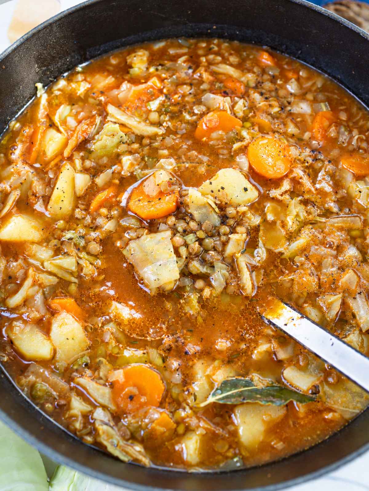 Cabbage lentil soup in a large pot with tender vegetables and potatoes.