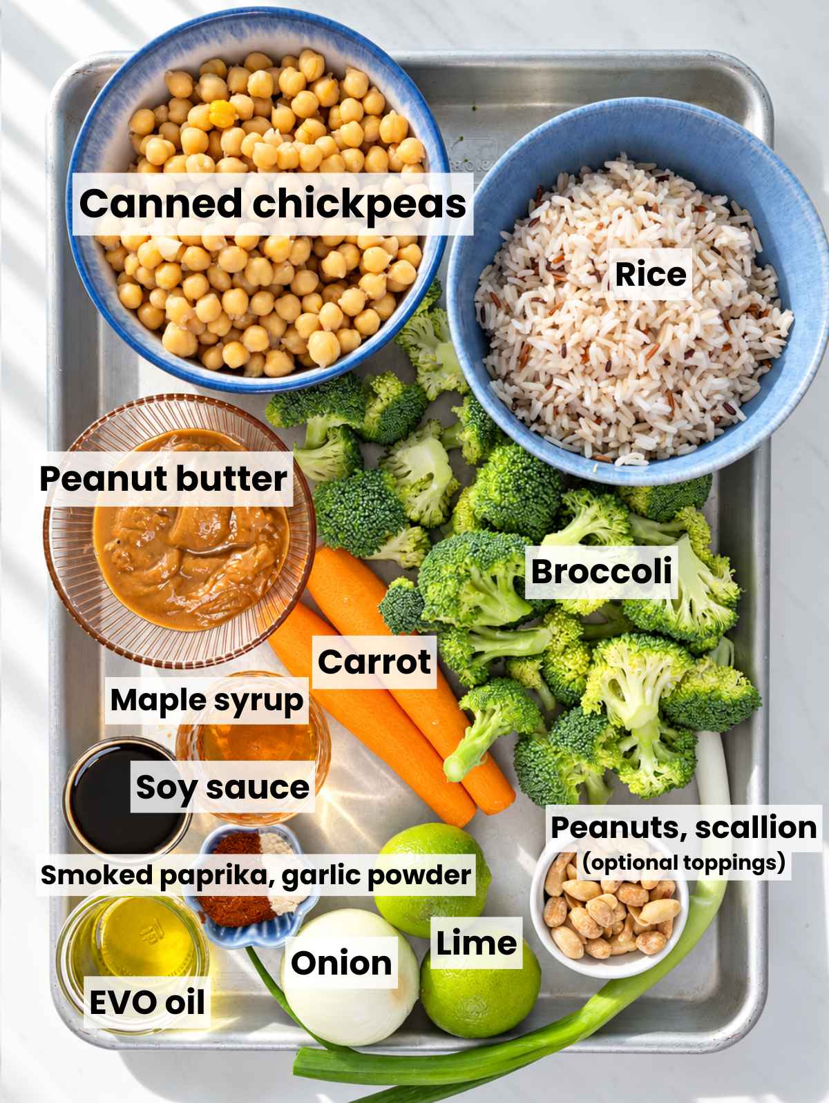 Chickpeas, carrots, broccoli, rice, peanut butter, and seasonings arranged on marble.