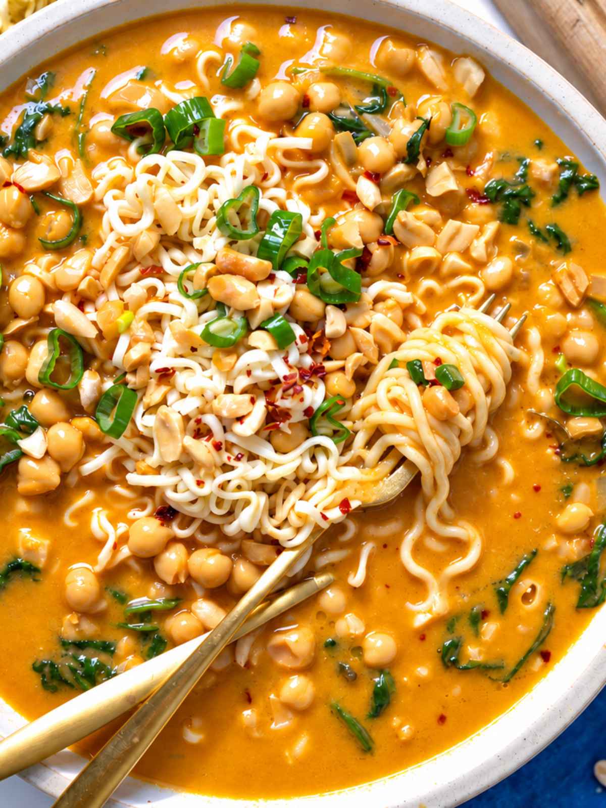 Close-up of noodles and chickpeas glistening in creamy peanut broth.