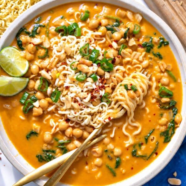 Creamy peanut butter noodle soup with chickpeas, topped with spring onions.