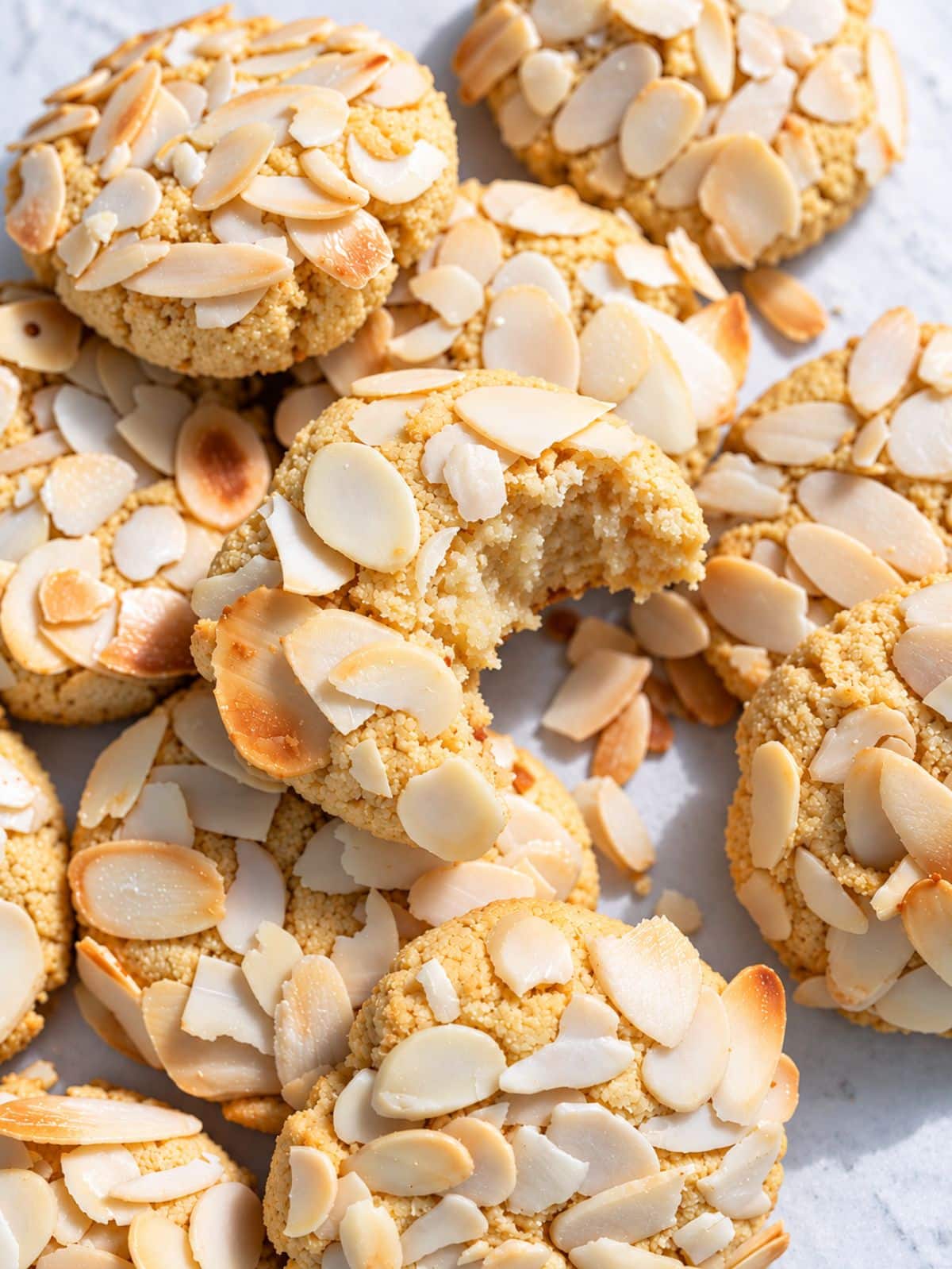 Golden almond croissant cookies topped with sliced almonds and powdered sugar.