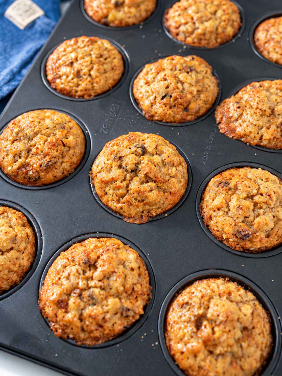 Golden banana oatmeal raisin muffins freshly baked in a nonstick muffin pan.
