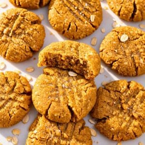 Golden peanut butter oat cookies arranged casually on a light marble surface.